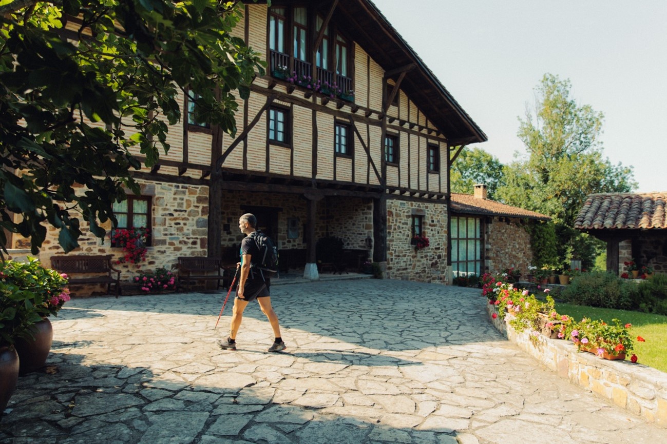 Senderista en la entrada de una casa rural en Euskadi